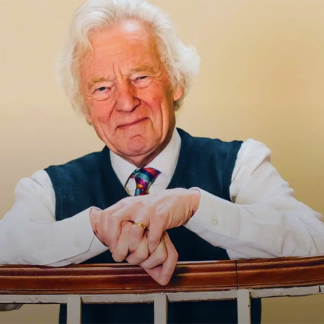 Man leaning on stair rail smiling into camera